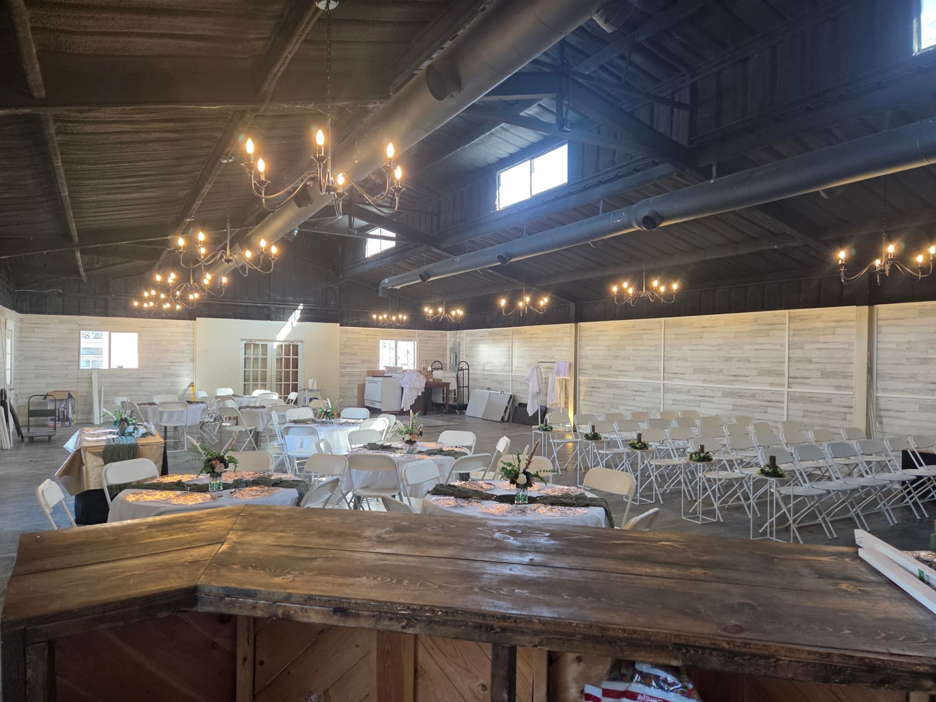 Open reception hall with chandeliers, round tables and ceremony seating