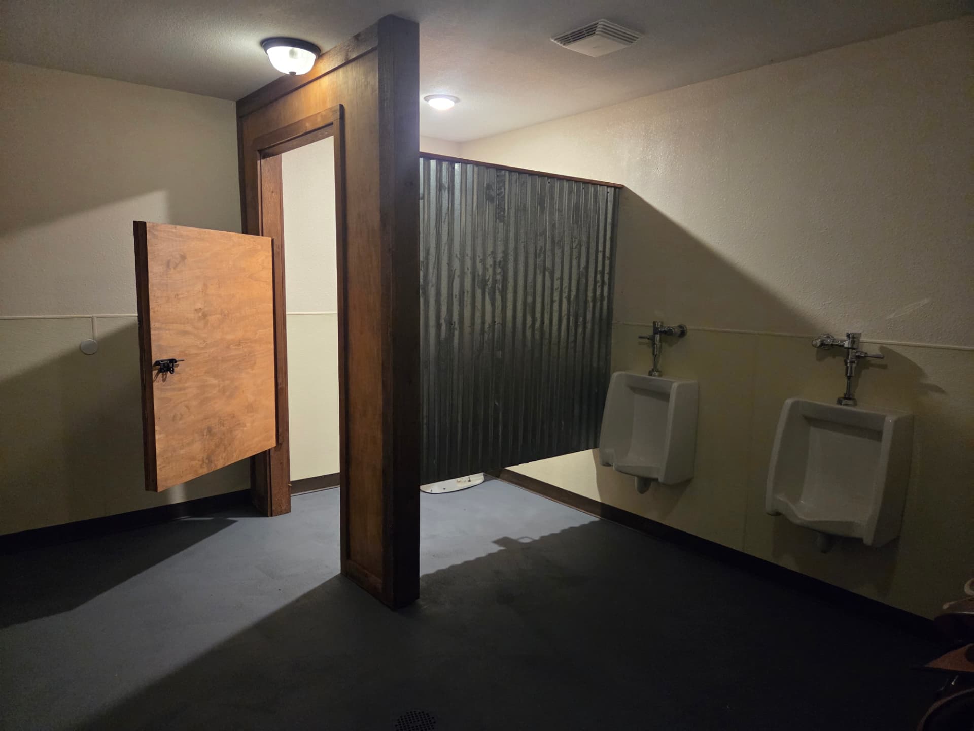 Restroom with corrugated metal partition and rustic timber framing